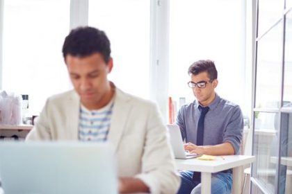 Business professionals collaborate on laptops, representing investment in the vet sector.