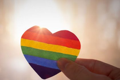 A hand holding a rainbow heart represents Relationships and Sexuality Education (RSE) in schools.