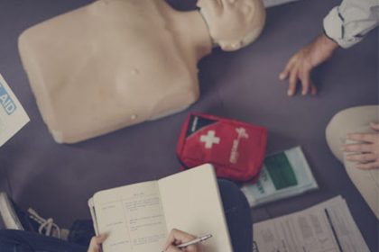 A first aid training session demonstrates emergency preparedness with a CPR mannequin and kit.